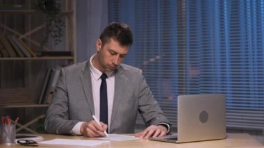 İşadamı kalem kontratıyla kontrol edip imzalıyor. Takım elbiseli patron ofisinde oturuyor. Çalışma evraklarını imzalamak, anlaşma ya da anlaşma, onay ortaklığı. Yavaş çekim hazır, 4K 59.94fps 'de..