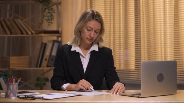 Бізнес-леді перевіряють і підписують за контрактом ручки. Жінка в чорному костюмі сидить за столом в офісі. Підписання робочих паперів, угод або угод, погодження партнерства. Повільний рух готовий, 4K на 59.94fps — стокове відео