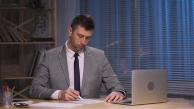 İşadamı kalem kontratıyla kontrol edip imzalıyor. Takım elbiseli patron ofisinde oturuyor. Çalışma evraklarını imzalamak, anlaşma ya da anlaşma, onay ortaklığı. Yavaş çekim hazır, 4K 59.94fps 'de..