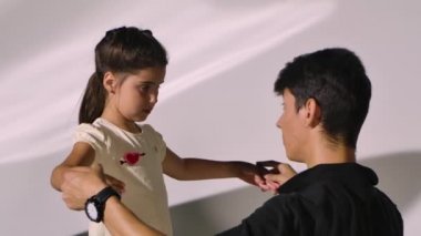 Küçük kız için kişisel bale dersi. Profesyonel öğretmen, kızlara dans öğeleri öğretir ve el hareketlerini düzeltir. Beyaz stüdyo arka planındaki sevimli bale öğrencisini kapat..
