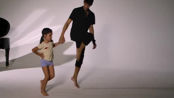 A szorgalmas kis balett hallgató egyéni balett órát tart professzionális tanárral. Férfi koreográfus ugrál a diákjával, miközben a balett elemeit tanulmányozza.. — Stock videók