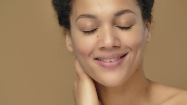 Beauty portrait of young African American woman, she gently touches face with her fingers. Black female model posing on brown studio background. Close up. Slow motion ready, 4K at 59.94fps. — Stock Video