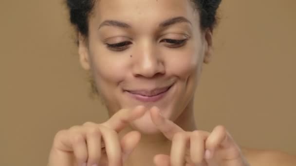 年轻的非洲裔美国妇女的美丽画像，微笑着，用手指表现出她的心。黑色女模特在棕色工作室的背景上摆姿势.靠近点慢动作准备，4K，59.94fps. — 图库视频影像