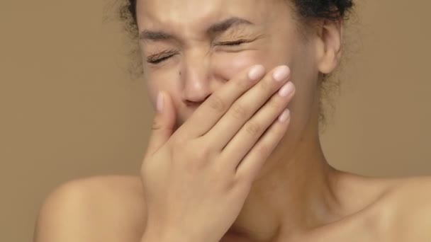 Retrato de belleza de bostezar joven mujer afroamericana está sufriendo de dolor de cuello. Modelo femenino negro posando sobre fondo de estudio marrón. De cerca. Cámara lenta lista, 4K a 59.94fps. — Vídeo de stock