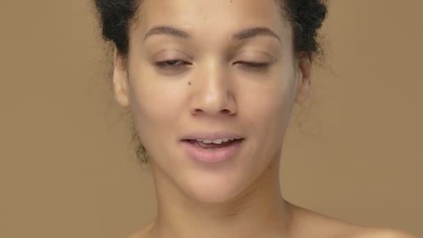 Retrato de belleza de una joven afroamericana sosteniendo enjuague bucal y cepillo de dientes, eligiendo. Mujer negra posando sobre fondo de estudio marrón. De cerca. Cámara lenta lista, 4K a 59.94fps. — Vídeo de stock