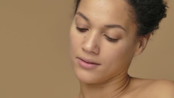 Schoonheidsportret van jonge Afro-Amerikaanse vrouw reinigen gezicht met witte wattenschijfje, het verwijderen van make-up. Zwart vrouwtje op bruine studioachtergrond. Sluit maar af. Slow motion klaar, 4K bij 59,94fps. — Stockvideo
