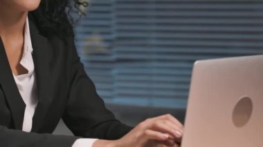 Afrikalı Amerikalı kadın portresi, kredi kartı ve dizüstü bilgisayarla online alışveriş yapıyor. İş kadını iş yerinde poz veriyor, ofiste masada oturuyor. Kapatın. Yavaş çekim hazır, 4K 59.94fps 'de..