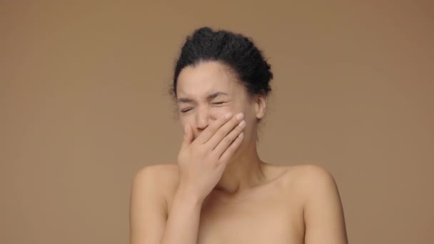 Retrato de belleza de bostezar joven mujer afroamericana está sufriendo de dolor de cuello. Modelo femenino negro posando sobre fondo de estudio marrón. Cámara lenta lista, 4K a 59.94fps. — Vídeo de stock