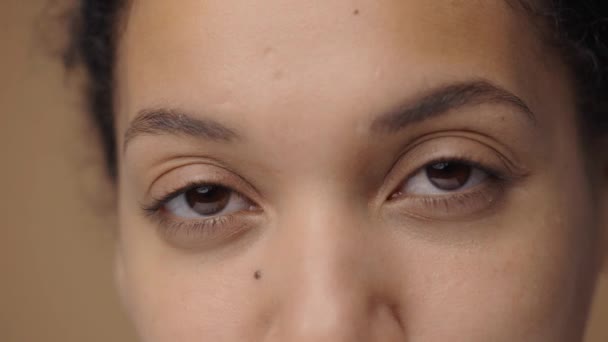 Bruna kvinnliga ögon ser rakt fram på allvar. Afrikansk amerikansk kvinna ögon med naturlig skönhet. Närbild makro porträtt med perfekt ren och slät hud. Slow motion klar, 4K vid 59.94fps. — Stockvideo
