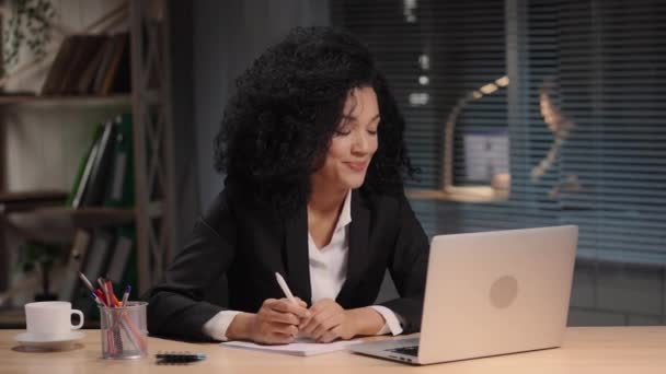 Porträt einer Afroamerikanerin im Businessanzug, Gespräche per Videoanruf per Laptop. Geschäftsfrau posiert am Arbeitsplatz, sitzt am Tisch im Büro. Zeitlupe bereit, 4K bei 59.94fps. — Stockvideo