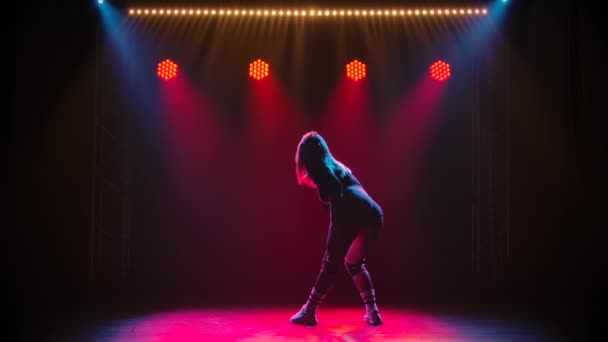Гнучка молода жінка рухає дупу, танцює в чорному леопарді. Силует привабливої танцівниці потискає їй сідниці в темній студії з червоними вогнями. Повільний рух . — стокове відео
