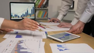 İş ortakları toplantıda şirketin ekonomik durumunu tartışıyor. Tablet ve dizüstü bilgisayar kullanarak grafik istatistiklerini izleyen bir grup kadın ve erkek. Kapatın. Yavaş çekim hazır, 4K 59.94fps 'de..