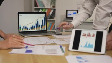 İş ortakları toplantıda şirketin ekonomik durumunu tartışıyor. Tablet ve dizüstü bilgisayar kullanarak grafik istatistiklerini izleyen bir grup kadın ve erkek. Kapatın. Yavaş çekim hazır, 4K 59.94fps 'de..
