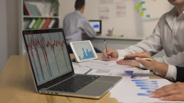 Homem e mulher vendo papéis com gráficos e gráficos, usando tablet laptop. Análise de estratégia de marketing, negociação no mercado de ações, trabalho em equipe corporativa. Fecha. Movimento lento pronto, 4K a 59.94fps. — Vídeo de Stock