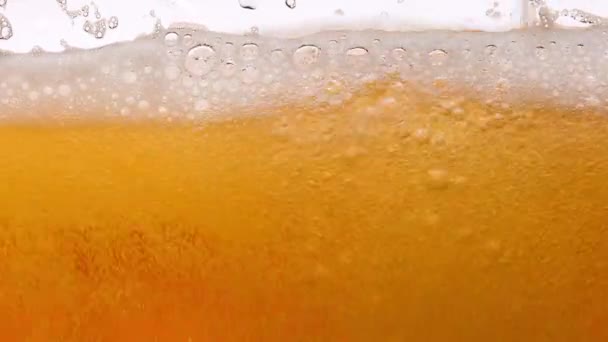 Macro cerveja leve em vidro. Um fino pedaço de líquido dourado derrama no vidro, criando muitas bolhas, ondas e espuma. Cerveja de bebida alcoólica acabada de fazer de perto. Movimento lento. — Vídeo de Stock