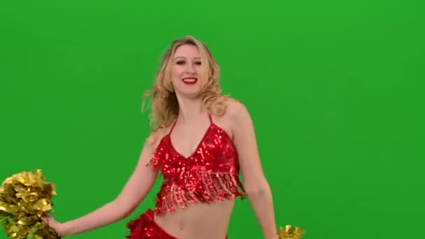 A cheering dance performed by a pretty cheerleader with pompoms in her hands in the studio on a green screen. A charming girl moves her arms and hips, twirls and waves her hair. Slow motion. Close up. — Stock Video