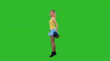 Bir ponpon kız coşkulu bir dans ediyor, dönüyor, zarafetle çömeliyor, dikey bölünme yapıyor. Sarı ve mavi üniformalı bir sarışın stüdyoda yeşil ekranda eğitim görüyor. Yavaş çekim.