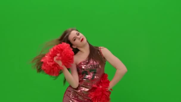 A charming girl moves her arms and hips, waves her hair. Long-haired cheerleader training in the studio on a green screen. Close up. Slow motion. — Stock Video