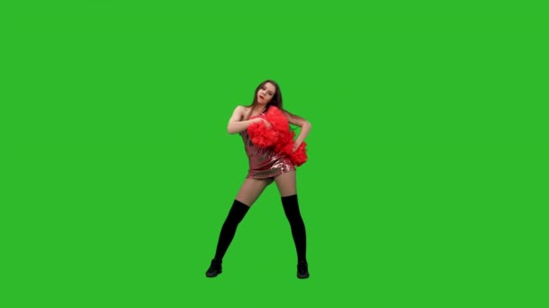 Animadora delgada con bailes de pelo largo con pompones rojos. La chica realiza un baile jubiloso en el estudio en una pantalla verde. Movimiento lento. — Vídeo de stock