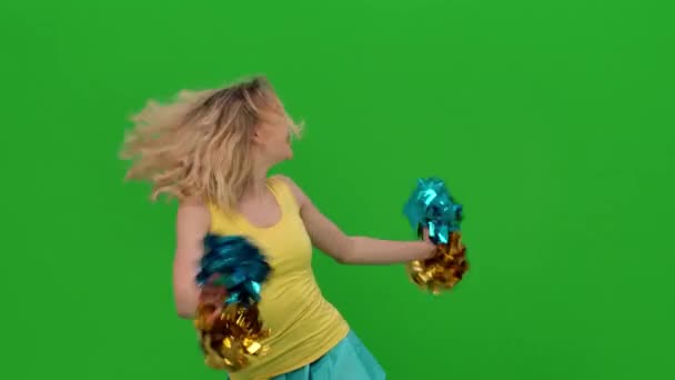 Een cheerleader danst een vurige cheerleader dans met pompons in de studio op een groen scherm. Het meisje beweegt haar heupen en armen, doet een verticale split, wervelt, buigt in een dans. Sluit maar af. Langzame beweging. — Stockvideo