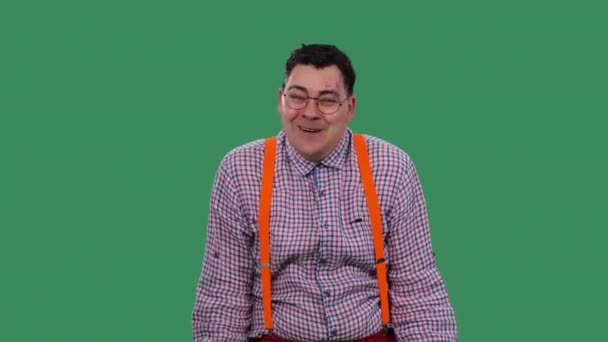 En förvånad chockad man med ett imponerat uttryck säger, herregud. Porträtt av en man i glasögon, i en rutig skjorta med orange hängslen i studion på en grön skärm. Sakta i backarna. Närbild. — Stockvideo