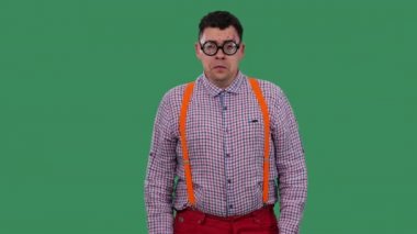 Gücenmiş bir adam, ağlıyor ve omuzlarını silkiyor. Kalın camlı gözlüklü, ekose gömlekli, turuncu askılı yeşil ekranlı bir adamın portresi. Ağır çekim. Kapat..