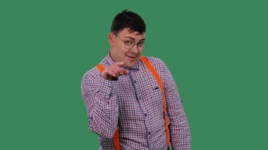 Adam işaret parmağını kameraya doğrultuyor ve parmağını boynunda gezdirip boğazını kesiyor. Stüdyoda yeşil ekranda gözlüklü bir adamın portresi. Ağır çekim. Kapat..