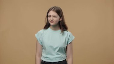 Çekici güzellik modelinin portresi parmağını olumsuz sallıyor ve hayır diyor, yasaklama hareketi. Beyaz tişörtlü genç kız kahverengi stüdyo arka planında poz veriyor. Kapatın. Yavaş çekim hazır 59.94fps.