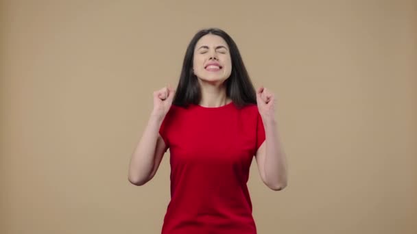 Retrato de una modelo con belleza natural mirando a la cámara con emoción, luego celebrando su triunfo victorioso. Joven morena posa sobre fondo de estudio marrón. De cerca. Cámara lenta lista 59.94fps. — Vídeos de Stock