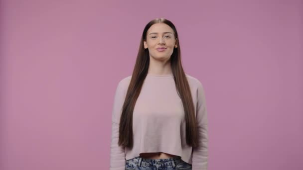 Retrato de una modelo de belleza mirando a la cámara y sonriendo. Chica joven con el pelo largo posa sobre fondo púrpura estudio. De cerca. Cámara lenta lista 59.94fps. — Vídeo de stock