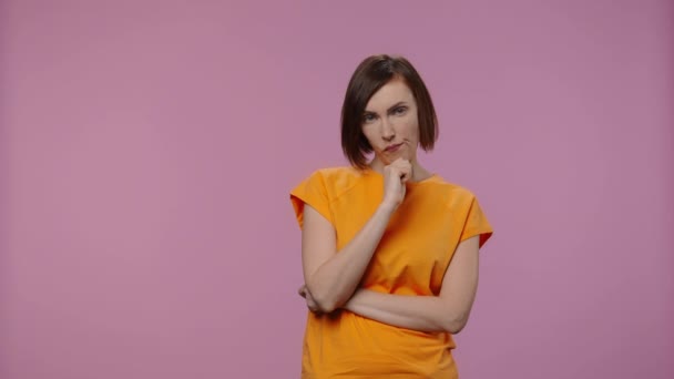 Portrait de charmant modèle pense à quelque chose, puis heureux qu'une idée lui vienne. Jeune femme en t-shirt jaune pose sur fond violet studio. Ferme là. Ralenti prêt 59.94fps. — Video