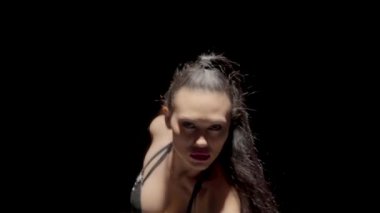Şehvetli genç kadın erotik olarak siyah stüdyo geçmişiyle ilgileniyor. Deri iç çamaşırlı dansçı cinsel olarak dans ediyor, esnek vücudunu eğiyor. Striptiz, git dans et, gece kulübü partisi. Kapatın. Yavaş çekim.