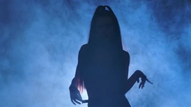 Siyah deri iç çamaşırlı seksi esmer silueti, mavi ışıklarla aydınlatılmış karanlık dumanlı bir stüdyoda erotik bir şekilde dans ediyor. Şehvetli striptizci dansı, özel dans, yürü, yürü. Kapatın. Yavaş çekim.