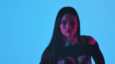 Siyah deri iç çamaşırlı seksi esmer, mavi ışıklarla aydınlatılmış karanlık bir stüdyoda erotik bir şekilde dans ediyor. Şehvetli striptizci dansı, özel dans, yürü, yürü. Siluet. Kapatın. Yavaş çekim.