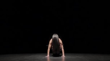 Şehvetli genç kadın erotik olarak siyah stüdyo geçmişiyle ilgileniyor. Deri iç çamaşırlı dansçı cinsel olarak dans ediyor, esnek vücudunu eğiyor. Striptiz, git dans et, gece kulübü partisi. Yavaş çekim.