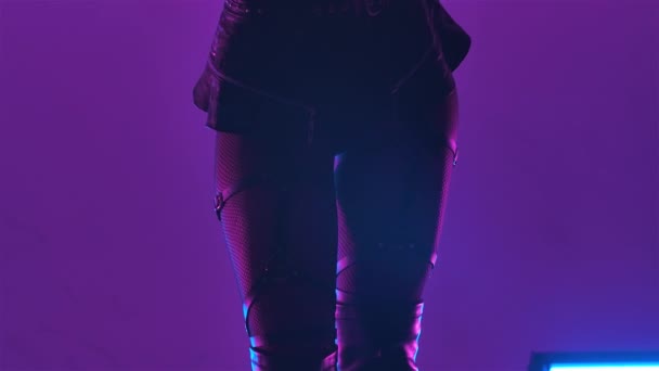 Sylwetka seksownej brunetki z długimi włosami w czarnej skórzanej bieliźnie zmysłowo tańczy w ciemnym studio z fioletowymi światłami. Zamknij drzwi. Zwolniony ruch. — Wideo stockowe
