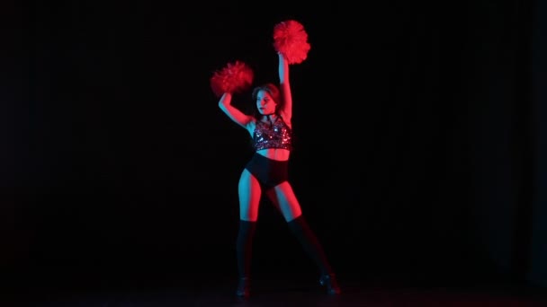 Prove di danza delle cheerleader con pompon su sfondo nero da studio con luci rosse e blu. Silhouette di giovane cheerleader che balla danza allegra, muovendo mani e fianchi. Movimento lento pronto 59.94fps. — Video Stock
