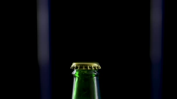 Macro shot of cap popping out of green glass bottle and explosion of splash carbonated beer. Amber liquid under pressure bursts out of bottle and fountains up. Black background. Close up. Slow motion. — Stock Video