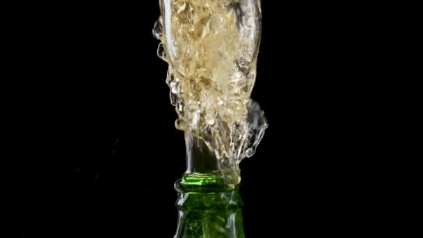 Macro shot of cap popping out of green glass bottle and explosion of splash carbonated beer. Amber liquid under pressure bursts out of bottle and fountains up. Black background. Close up. Slow motion. — Stockvideo