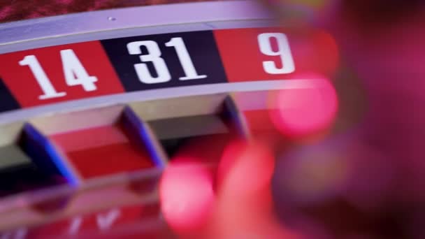 Una ruleta de casino con una bola blanca en verde 0. Mesa de juego de casino, números de cerca. Parte de la rueda de la ruleta corre en cámara lenta. Enfoque selectivo, bokeh. — Vídeo de stock