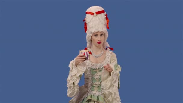 Portrait of courtier lady in vintage lace dress and wig, holding fries and showing thumbs down dislike. Young woman posing in studio with blue screen background. Close up. Slow motion ready 59.94fps. — стоковое видео