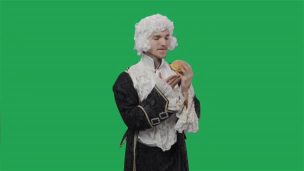 Retrato de caballero cortesano en traje vintage histórico negro y peluca, saboreando olor a hamburguesa con queso. Hombre joven posando en el estudio con fondo de pantalla verde. De cerca. Cámara lenta lista 59.94fps. — Vídeo de stock