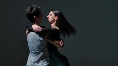 Romantik dansçılar tarafından yapılan şehvetli çağdaş dans. Genç adam ve kadın tutkuyla dans ediyor, gri stüdyo arka planında birbirlerine nazikçe sarılıp dokunuyorlar. Kapatın. Yavaş çekim.