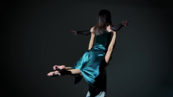 Un couple de jeunes danseurs dansant la chorégraphie moderne en studio sur un fond gris foncé. L'homme entoure la femme en soutien. Ferme là. Mouvement lent. — Video