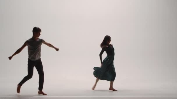 Elementos de la coreografía moderna, contemporánea interpretada por una joven pareja de bailarines sobre un fondo de estudio blanco. Hombre y mujer bailan apasionadamente, expresando sus sentimientos en un baile. Movimiento lento. — Vídeos de Stock