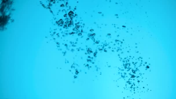 Le flux d'eau au ralenti tombe dans un réservoir d'eau, créant des bulles d'air, laissant tomber des éclaboussures après la chute. Fraicheur d'un liquide bleu clair versé dans un récipient transparent sur fond bleu