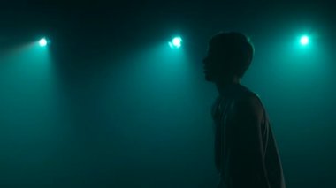 Genç bir basketbolcunun silueti. Duman ve mavi ışıklarla karanlık bir arka planda atış çalışması yapıyor. Kapatın. Yan görüş. Yavaş çekim hazır 59.94fps.