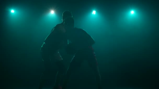 Silhouettes of two guys basketball players practicing skills of attack, dribbling and defense. Tall rivals compete in basketball in dark studio with smoke and blue lights. Slow motion ready 59.94fps. — Stock Video