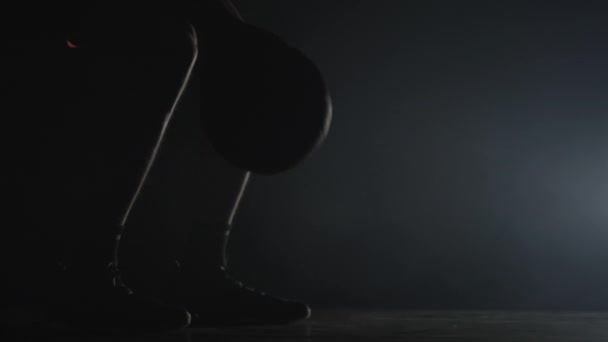 Silhouette of basketball player dribbles ball practicing skills in a dark studio with smoke and backlight. Male feet close up. Slow motion ready 59.94fps. — Stock Video