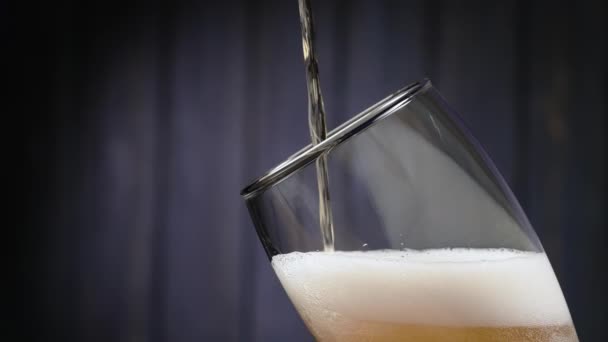 Μπύρα χύνεται και αφρούς σε ένα ποτήρι σε μαύρο φόντο. Ένα ποτήρι δροσερή νόστιμη craft μπύρα. Φρεσκάδα και αφρός. Αργή κίνηση. Κλείσε.. — Αρχείο Βίντεο